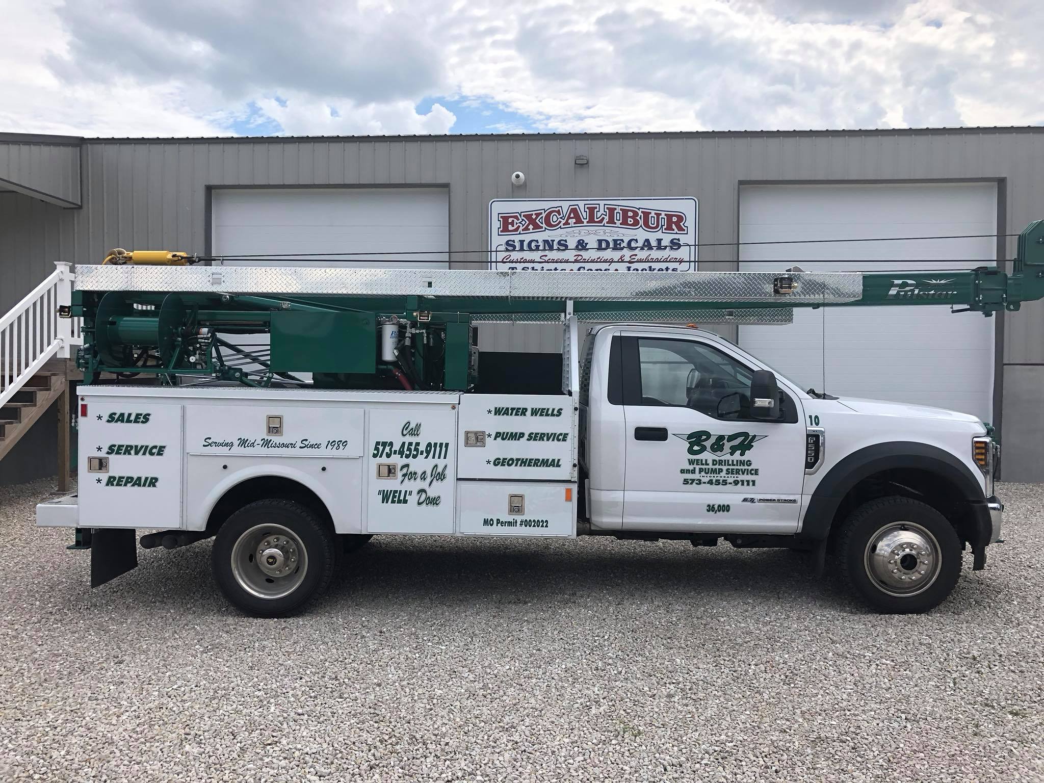 White service truck with custom door lettering parked in front of the Excalibur Signs & Decals shop