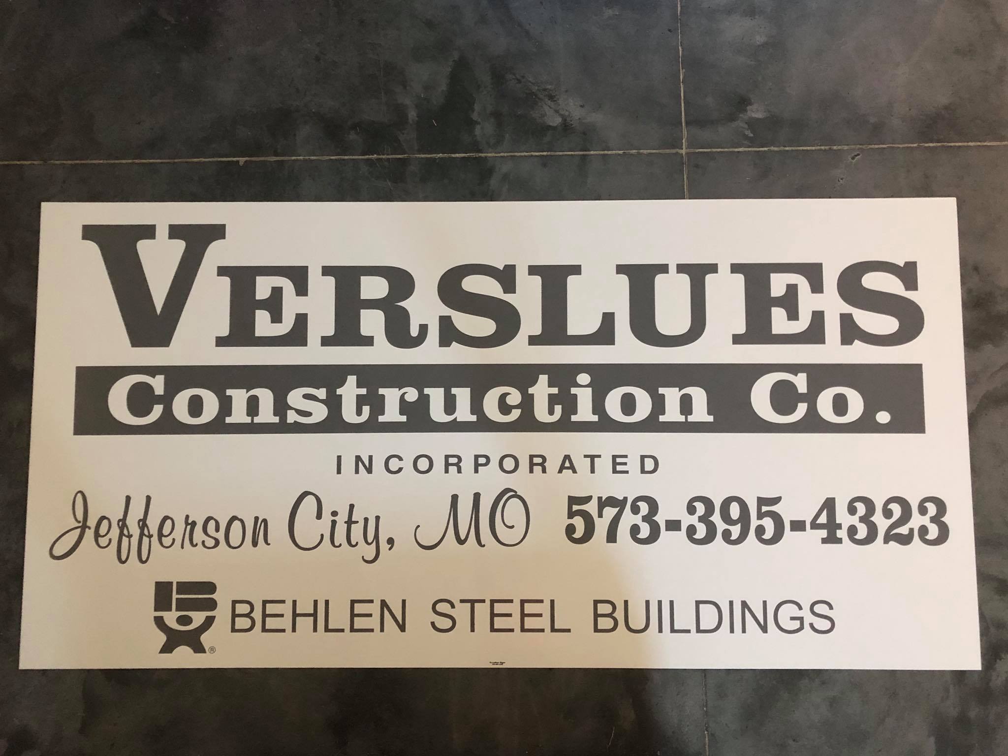 Printed sign for a construction company with its name and phone number